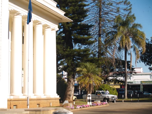 White columns at Bulawayo City Hall with palms and trees beside the building.
