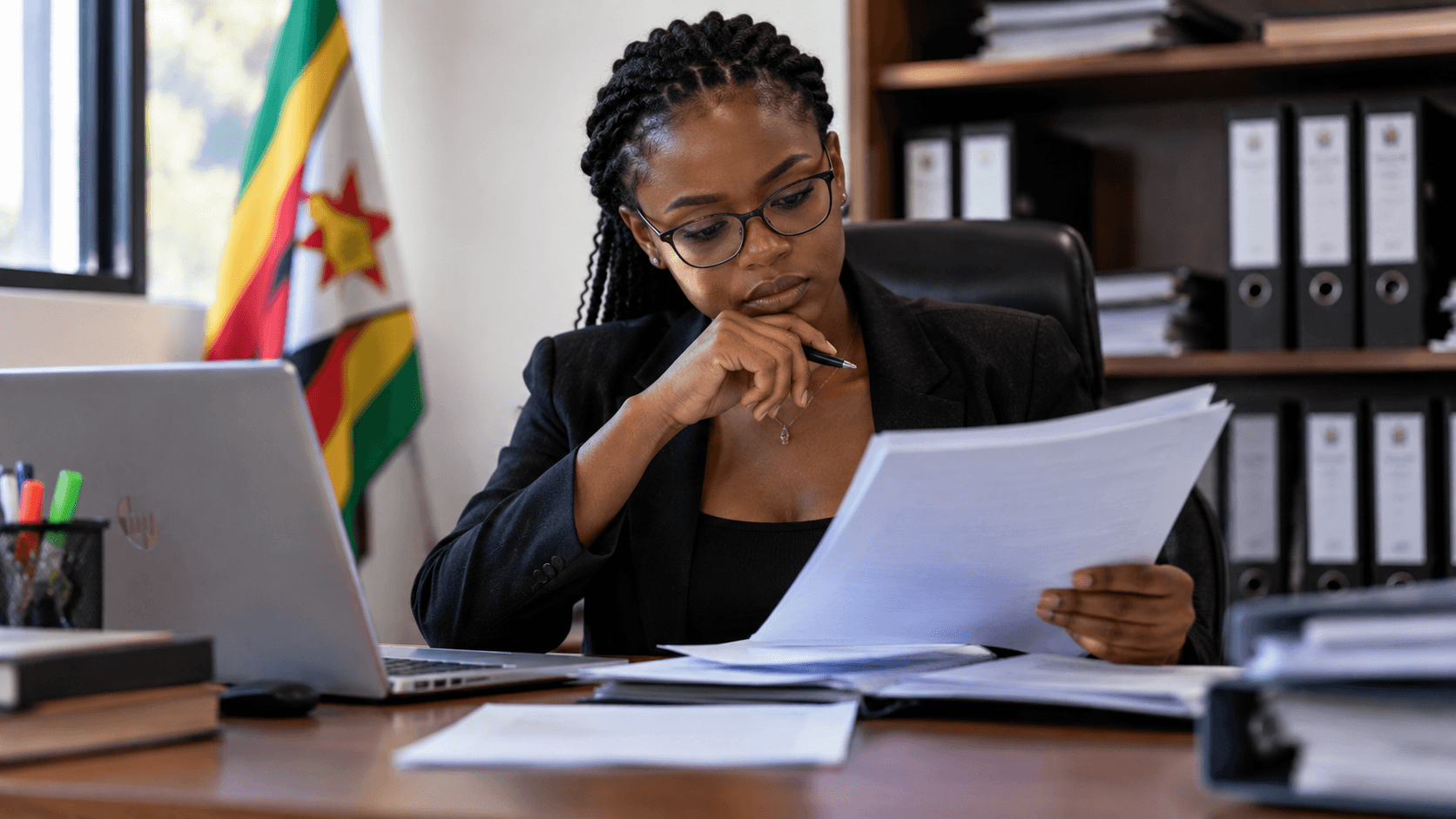 Illustration of a Zimbabwean professional reviewing employment documents at an office desk.
